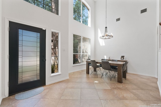 tiled entrance foyer with an inviting chandelier and a towering ceiling