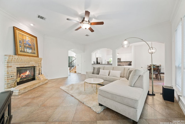 living room featuring ceiling fan, ornamental molding, and a fireplace