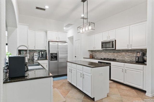 kitchen with appliances with stainless steel finishes, backsplash, white cabinets, and a center island