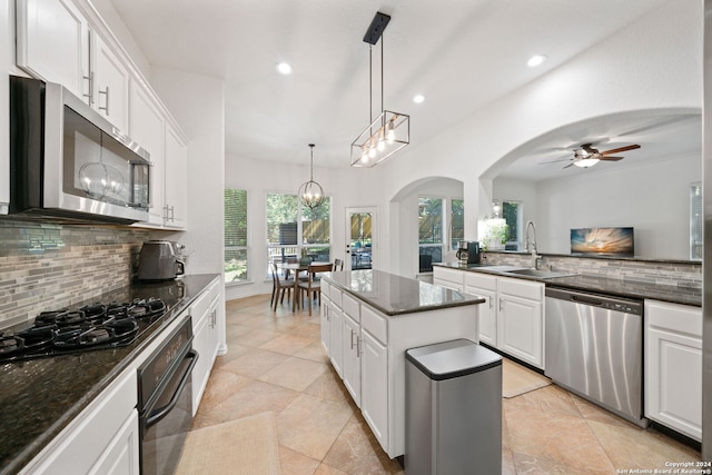 kitchen featuring a kitchen island, decorative light fixtures, white cabinetry, stainless steel appliances, and decorative backsplash