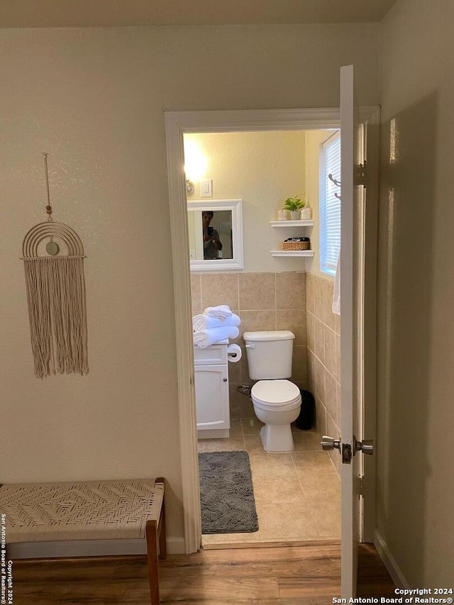 bathroom with wood-type flooring, vanity, toilet, and tile walls