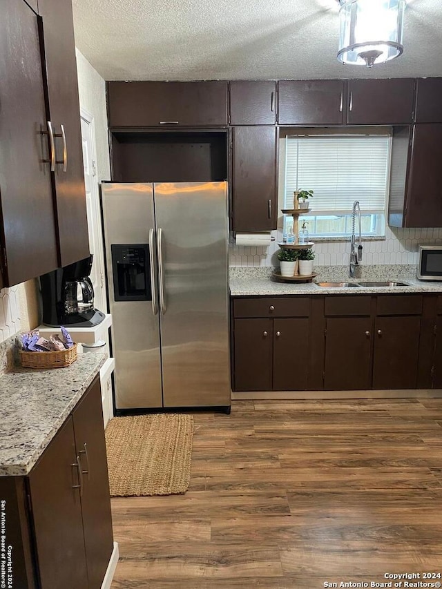 kitchen with backsplash, sink, dark brown cabinets, wood-type flooring, and stainless steel appliances