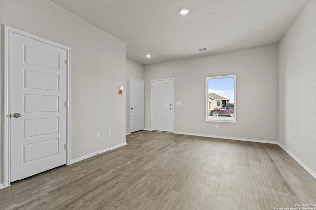 spare room featuring a textured ceiling and light hardwood / wood-style flooring