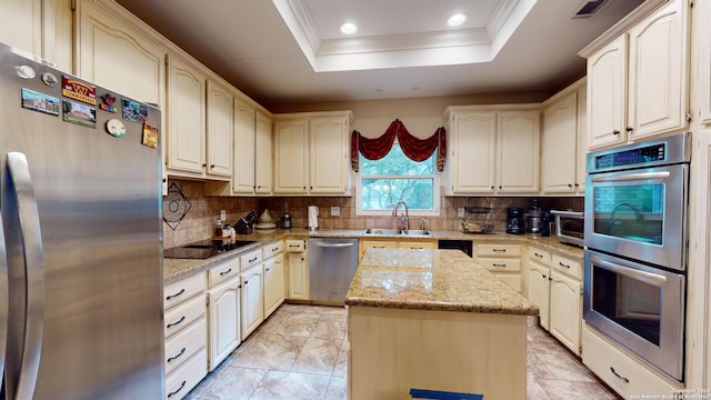 kitchen featuring sink, a raised ceiling, a kitchen island, stainless steel appliances, and light stone countertops