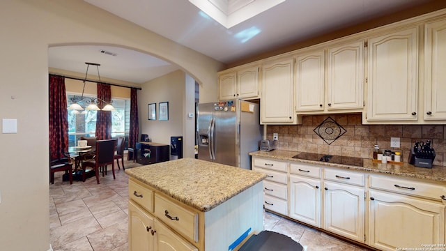 kitchen featuring pendant lighting, tasteful backsplash, light stone countertops, a kitchen island, and stainless steel fridge with ice dispenser