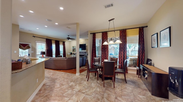 dining area with a fireplace and ceiling fan with notable chandelier