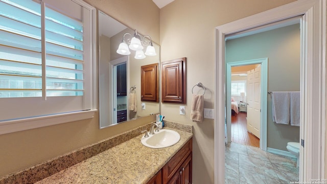 bathroom featuring vanity, an inviting chandelier, and toilet