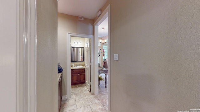 hallway with sink, light tile patterned floors, and an inviting chandelier