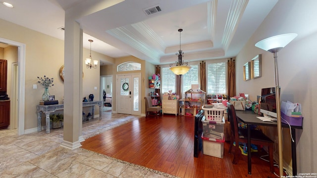 foyer entrance with crown molding, light hardwood / wood-style flooring, a chandelier, and a tray ceiling