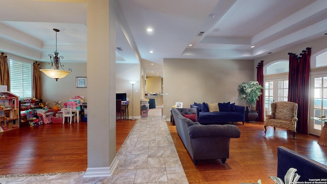 living room featuring french doors, light wood-type flooring, and a tray ceiling