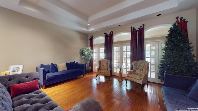 living room with french doors, wood-type flooring, and a tray ceiling