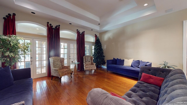 living room with wood-type flooring, a raised ceiling, and french doors