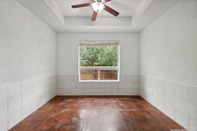 spare room featuring a raised ceiling and ceiling fan