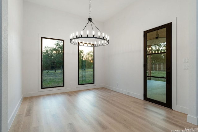 unfurnished dining area featuring light hardwood / wood-style floors and an inviting chandelier