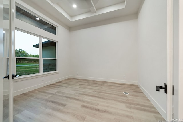 empty room featuring a tray ceiling and light hardwood / wood-style flooring