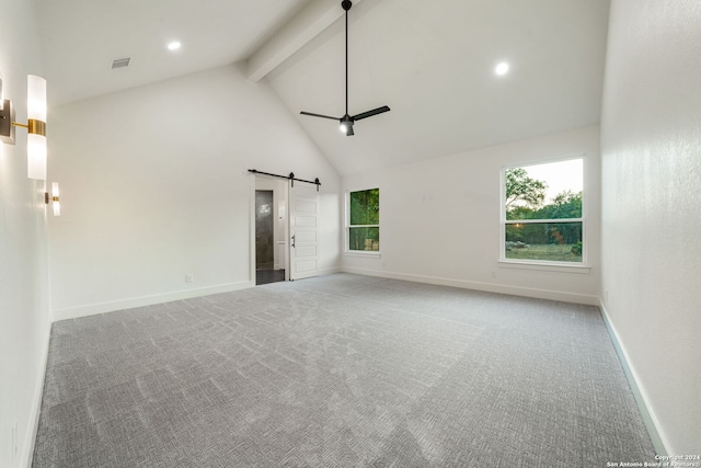 carpeted empty room with beamed ceiling, ceiling fan, a barn door, and high vaulted ceiling