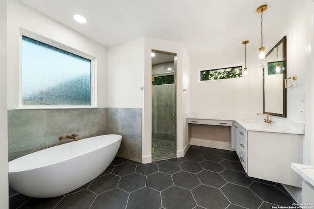 bathroom with separate shower and tub, tile patterned flooring, vanity, and tile walls