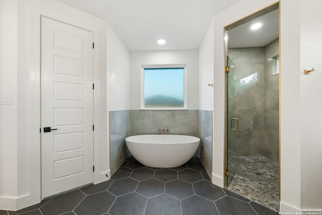 bathroom with separate shower and tub, tile patterned flooring, and tile walls