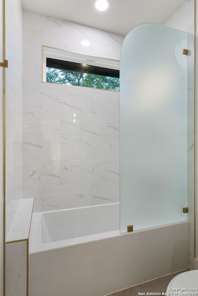 bathroom featuring toilet and tiled shower / bath