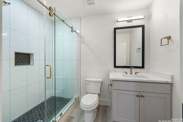 bathroom featuring a shower with door, vanity, wood-type flooring, and toilet