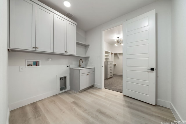 washroom with sink, cabinets, hookup for an electric dryer, hookup for a washing machine, and light hardwood / wood-style floors