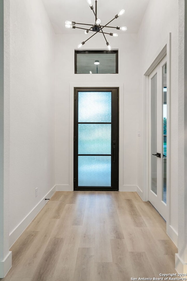 foyer with french doors, a chandelier, and light wood-type flooring