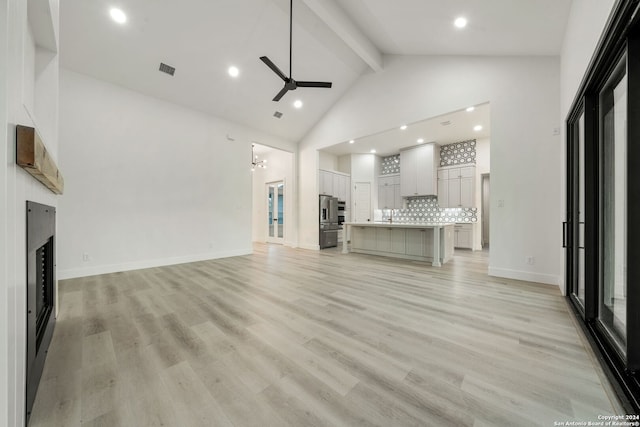 unfurnished living room with ceiling fan, beam ceiling, light wood-type flooring, and high vaulted ceiling