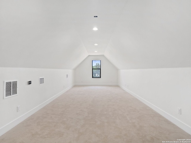 additional living space featuring lofted ceiling and light carpet