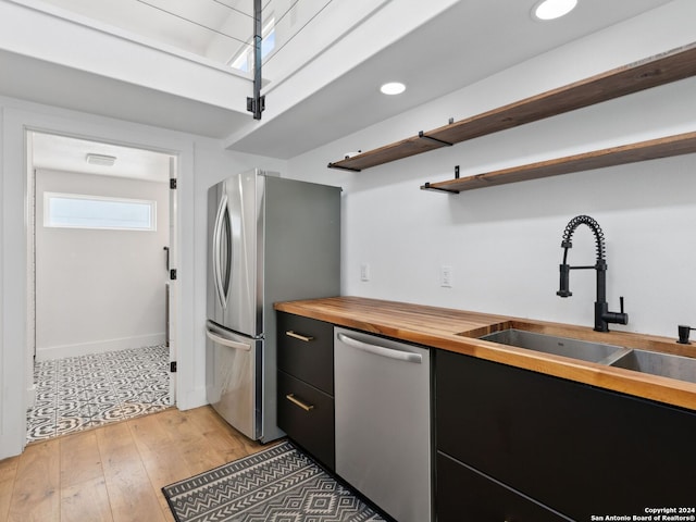 kitchen featuring wooden counters, stainless steel appliances, light hardwood / wood-style flooring, and sink