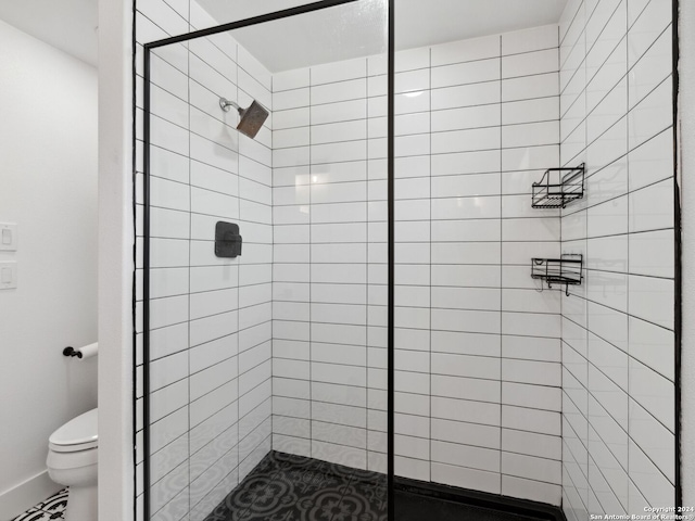 bathroom with a tile shower and toilet