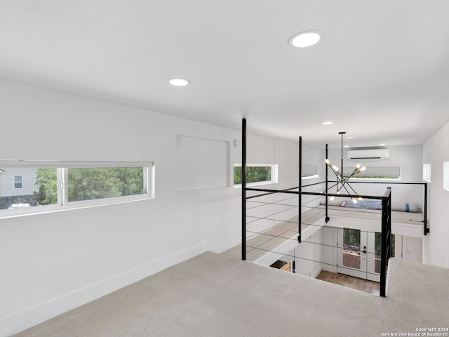 interior space with a wall mounted air conditioner, multiple windows, light carpet, and an inviting chandelier