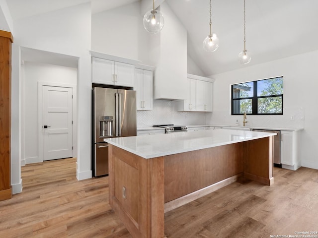 kitchen with white cabinets, a center island, stainless steel appliances, and high vaulted ceiling