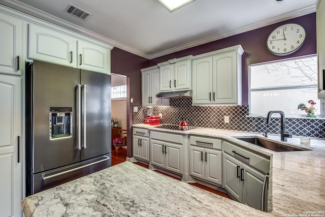 kitchen featuring ornamental molding, high end refrigerator, light stone countertops, and sink