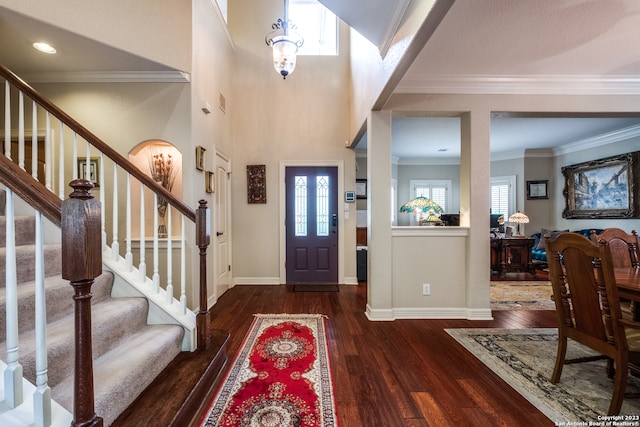 foyer entrance featuring ornamental molding, a towering ceiling, and dark wood-type flooring