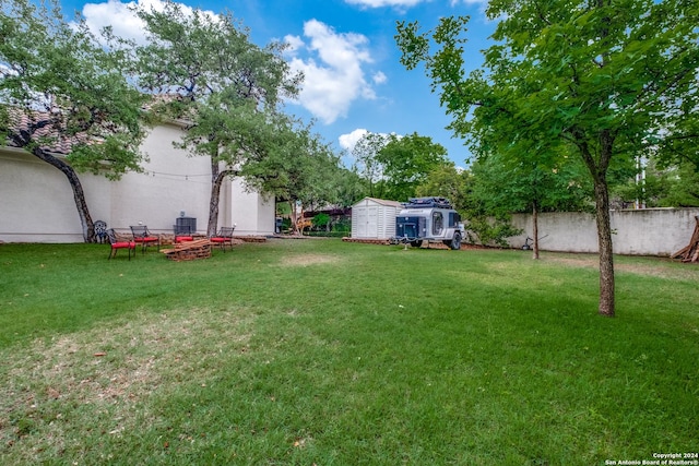 view of yard featuring an outdoor fire pit and a storage unit