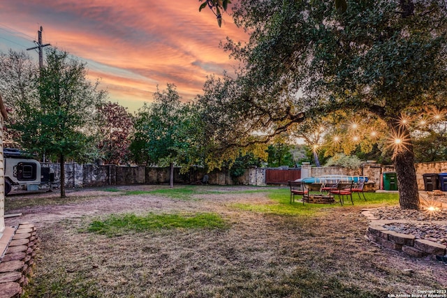 yard at dusk featuring a pool