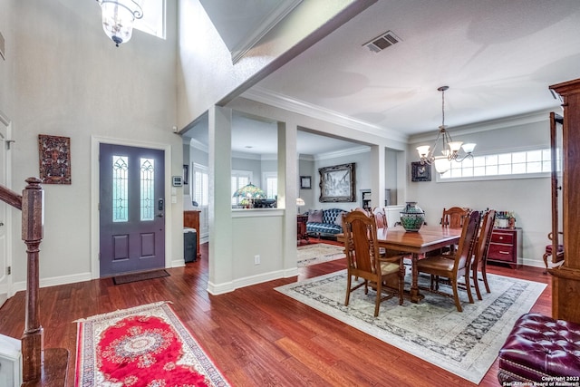 dining room featuring dark wood-type flooring, a notable chandelier, crown molding, and a wealth of natural light