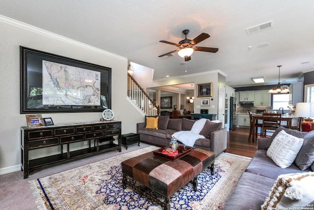 living room featuring ornamental molding and ceiling fan with notable chandelier