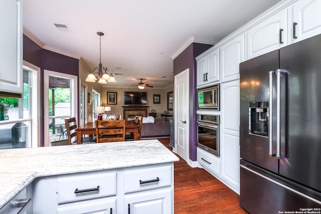 kitchen with white cabinetry, hanging light fixtures, light stone counters, and appliances with stainless steel finishes