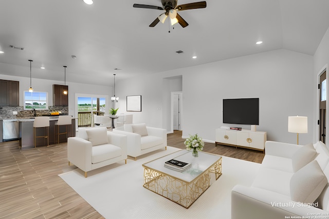 living room featuring vaulted ceiling, ceiling fan, and light wood-type flooring