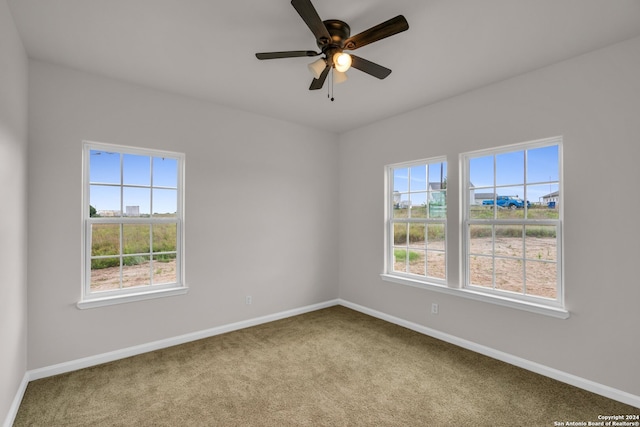 carpeted spare room featuring ceiling fan and a healthy amount of sunlight