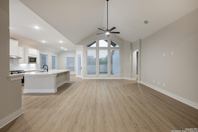 kitchen with a center island with sink, sink, decorative backsplash, white cabinetry, and stainless steel appliances