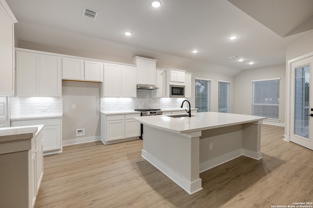 kitchen featuring light wood-type flooring, built in microwave, a kitchen island with sink, sink, and white cabinets