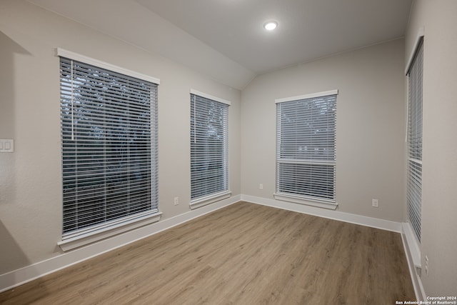 spare room with light hardwood / wood-style flooring and vaulted ceiling