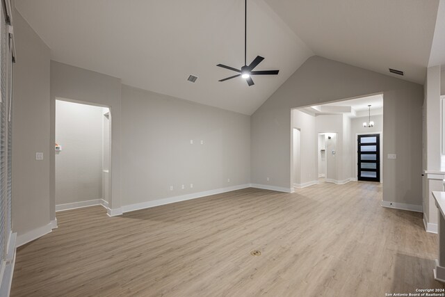 unfurnished living room featuring ceiling fan with notable chandelier, light wood-type flooring, and vaulted ceiling