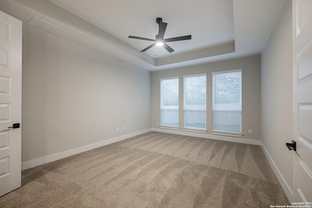 spare room featuring carpet flooring, a tray ceiling, and ceiling fan