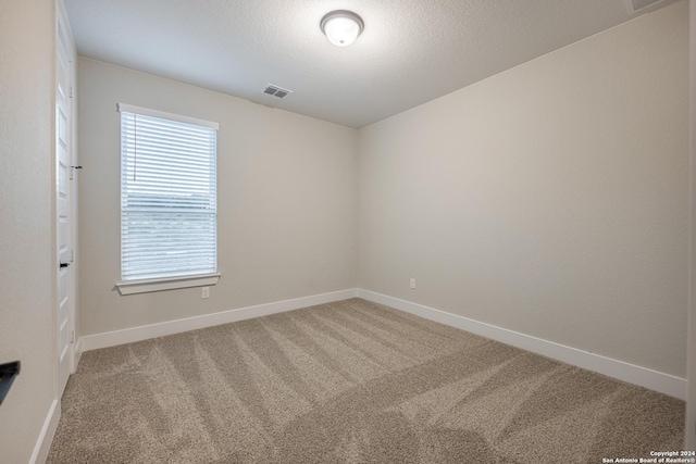 carpeted empty room featuring a textured ceiling