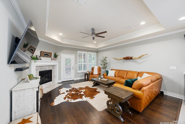 living room with a fireplace, ornamental molding, dark hardwood / wood-style floors, and a tray ceiling