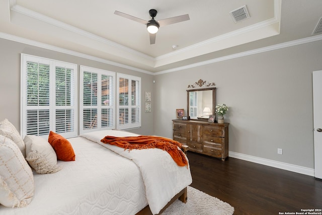 bedroom with ceiling fan, dark hardwood / wood-style flooring, ornamental molding, and a tray ceiling