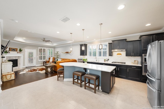 kitchen featuring a center island, hanging light fixtures, stainless steel appliances, light hardwood / wood-style flooring, and a kitchen bar